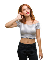 Wall Mural - Young beautiful woman over isolated background smiling with hand over ear listening an hearing to rumor or gossip. Deafness concept.