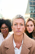 Vertical portrait a group of multiracial serious business women of diverse ages looking at the camera with serious and relaxed expression. A Caucasian woman with short hair standing in foreground