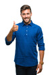 © Krakenimages.com - Young handsome man over isolated background doing happy thumbs up gesture with hand. Approving expression looking at the camera with showing success.