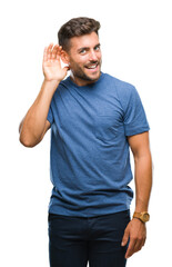 Wall Mural - Young handsome man over isolated background smiling with hand over ear listening an hearing to rumor or gossip. Deafness concept.