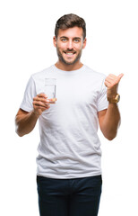 Wall Mural - Young handsome man drinking glass of water over isolated background pointing and showing with thumb up to the side with happy face smiling