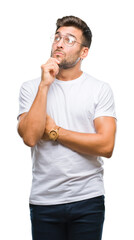 Wall Mural - Young handsome man wearing glasses over isolated background with hand on chin thinking about question, pensive expression. Smiling with thoughtful face. Doubt concept.