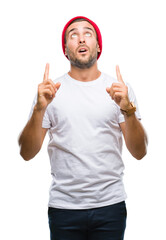 Canvas Print - Young handsome man over isolated background amazed and surprised looking up and pointing with fingers and raised arms.