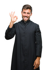 Sticker - Young catholic christian priest man over isolated background smiling positive doing ok sign with hand and fingers. Successful expression.