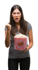 Sticker - Young beautiful hispanic eating popcorn annoyed and frustrated shouting with anger, crazy and yelling with raised hand, anger concept