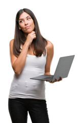 Sticker - Young hispanic woman using computer laptop serious face thinking about question, very confused idea