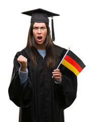 Poster - Young hispanic woman wearing graduated uniform holding flag of germany annoyed and frustrated shouting with anger, crazy and yelling with raised hand, anger concept