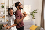 Fototapeta  - Joyful Young Couple Sharing a Dance in Their Cozy Living Room, Radiating Positive Energy and Togetherness in a Casual Setting.