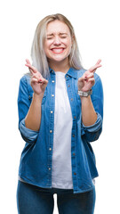 Sticker - Young blonde woman over isolated background smiling crossing fingers with hope and eyes closed. Luck and superstitious concept.