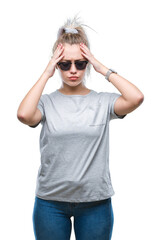 Wall Mural - Young blonde woman wearing sunglasses over isolated background suffering from headache desperate and stressed because pain and migraine. Hands on head.