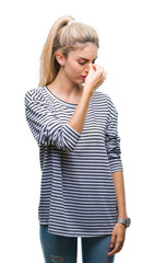 Canvas Print - Young beautiful blonde woman wearing stripes sweater over isolated background tired rubbing nose and eyes feeling fatigue and headache. Stress and frustration concept.