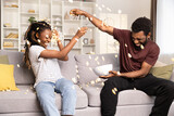 Fototapeta Zachód słońca - Joyful Couple Having Fun With Popcorn On Couch. African American Man And Woman Enjoying Playful Time, Home Entertainment. Lifestyle, Leisure, Togetherness Concept Captured. 