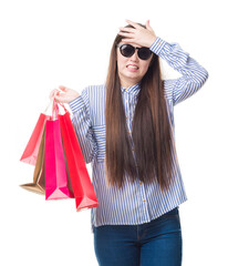 Canvas Print - Young Chinese woman over isolated background holding shopping bags on sales stressed with hand on head, shocked with shame and surprise face, angry and frustrated. Fear and upset for mistake.