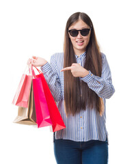 Wall Mural - Young Chinese woman over isolated background holding shopping bags on sales very happy pointing with hand and finger