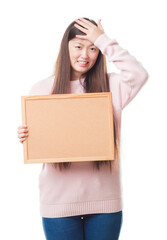 Canvas Print - Young Chinese woman over isolated background holding corkboard stressed with hand on head, shocked with shame and surprise face, angry and frustrated. Fear and upset for mistake.