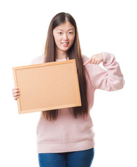 Wall Mural - Young Chinese woman over isolated background holding corkboard with surprise face pointing finger to himself