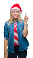 Poster - Young caucasian woman wearing christmas hat over isolated background pointing finger up with successful idea. Exited and happy. Number one.