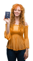 Wall Mural - Young redhead woman holding passport of Germany with a happy face standing and smiling with a confident smile showing teeth