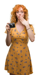 Wall Mural - Young redhead woman taking pictures holding vintage camera cover mouth with hand shocked with shame for mistake, expression of fear, scared in silence, secret concept