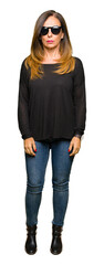 Wall Mural - beautiful middle age woman wearing sunglasses with serious expression on face. simple and natural lo