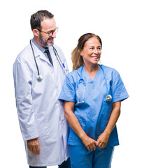 Poster - Middle age hispanic doctors partners couple wearing medical uniform over isolated background looking away to side with smile on face, natural expression. Laughing confident.