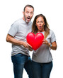 © Krakenimages.com - Middle age hispanic casual couple in love holding red heart over isolated background scared in shock with a surprise face, afraid and excited with fear expression
