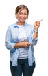 © Krakenimages.com - Middle age senior hispanic woman over isolated background with a big smile on face, pointing with hand and finger to the side looking at the camera.