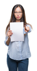 Sticker - Young asian woman holding blank paper over isolated background pointing with finger to the camera and to you, hand sign, positive and confident gesture from the front