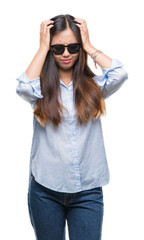 Wall Mural - Young asian woman wearing sunglasses over isolated background suffering from headache desperate and stressed because pain and migraine. Hands on head.