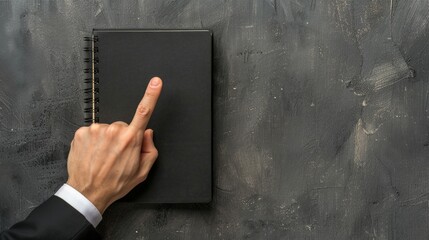 Canvas Print - Someone pointing at a dark notepad on a concrete wall