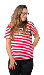 Canvas Print - Young beautiful brunette woman wearing glasses and stripes t-shirt over isolated background looking away to side with smile on face, natural expression. Laughing confident.