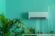 A white air conditioner is mounted on the wall in front of a green wall. Summer heat concept