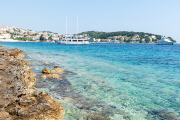 Sticker - View from rugged rocky coastline across harbour to tourist and fishing township of Hvar with tour boats at anchor.