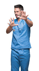 Poster - Handsome young doctor surgeon man over isolated background afraid and terrified with fear expression stop gesture with hands, shouting in shock. Panic concept.