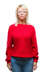 Wall Mural - Young beautiful blonde woman wearing sweater and glasses over isolated background with serious expression on face. Simple and natural looking at the camera.