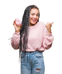 Poster - Young african american girl eating pink donut over isolated background pointing and showing with thumb up to the side with happy face smiling