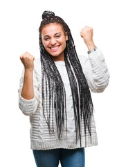 Poster - Young braided hair african american girl wearing sweater over isolated background very happy and excited doing winner gesture with arms raised, smiling and screaming for success. Celebration concept.