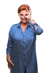 Poster - Atrractive senior caucasian redhead woman over isolated background doing ok gesture with hand smiling, eye looking through fingers with happy face.