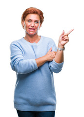 Poster - Atrractive senior caucasian redhead woman over isolated background with a big smile on face, pointing with hand and finger to the side looking at the camera.