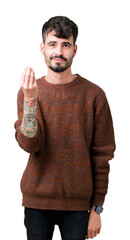 Wall Mural - Young handsome man wearing winter sweater over isolated background Doing Italian gesture with hand and fingers confident expression