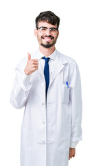 Wall Mural - Young professional scientist man wearing white coat over isolated background doing happy thumbs up gesture with hand. Approving expression looking at the camera showing success.