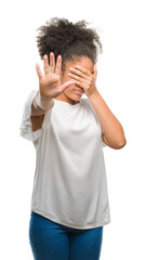 Poster - Young afro american woman over isolated background covering eyes with hands and doing stop gesture with sad and fear expression. Embarrassed and negative concept.