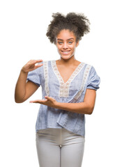 Poster - Young afro american woman over isolated background gesturing with hands showing big and large size sign, measure symbol. Smiling looking at the camera. Measuring concept.