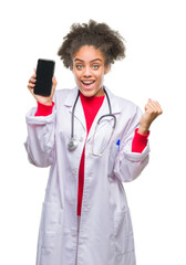 Canvas Print - Young afro american doctor woman using smartphone over isolated background screaming proud and celebrating victory and success very excited, cheering emotion