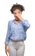 © Krakenimages.com - Young afro american woman over isolated background peeking in shock covering face and eyes with hand, looking through fingers with embarrassed expression.