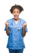 © Krakenimages.com - Young afro american doctor woman over isolated background celebrating surprised and amazed for success with arms raised and open eyes. Winner concept.