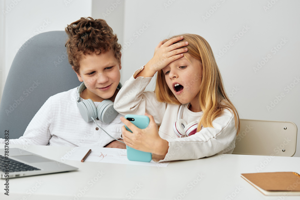 Happy Caucasian boy and girl studying together at home, using their ...
