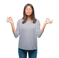 Wall Mural - Young asian woman wearing glasses over isolated background relax and smiling with eyes closed doing meditation gesture with fingers. Yoga concept.