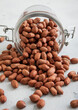 Raw healthy red peanut nuts in glass jar on white kitchen table.Macro.