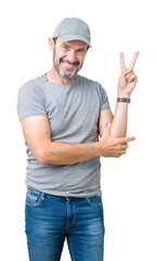 Wall Mural - Handsome middle age hoary senior man wearing sport cap over isolated background smiling with happy face winking at the camera doing victory sign. Number two.